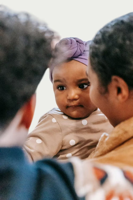Two children looking at a baby in a mirror