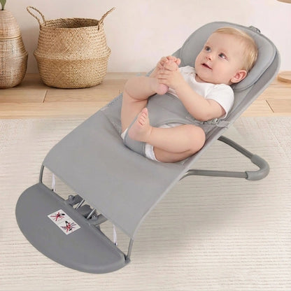 Baby in a gray baby bouncer on a light wooden floor with woven baskets in the background.