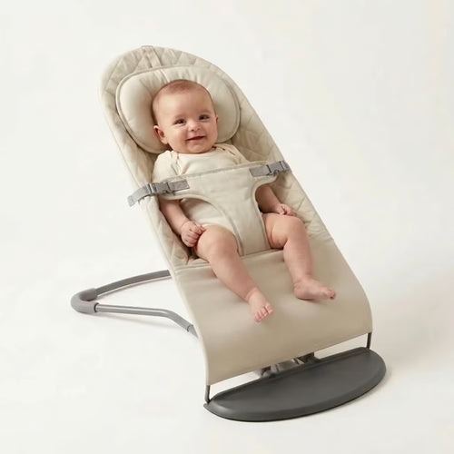 Baby in a beige baby bouncer on a white background