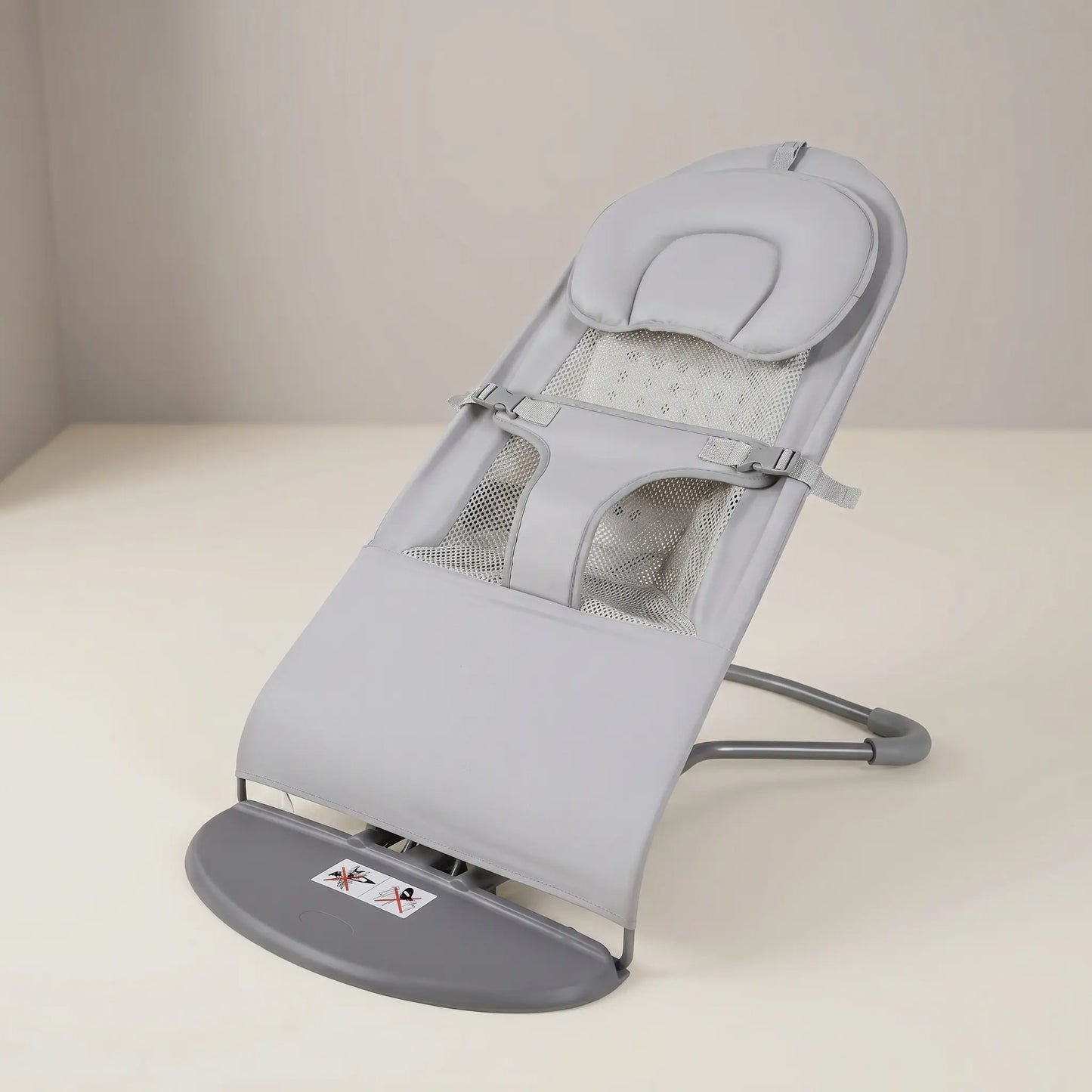 Gray baby bouncer on a white surface with a neutral background