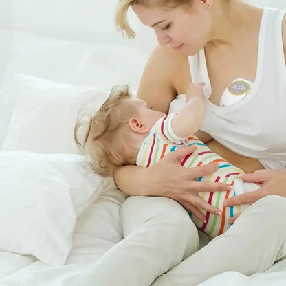 Woman breastfeeding baby while wearing electric breast pump.