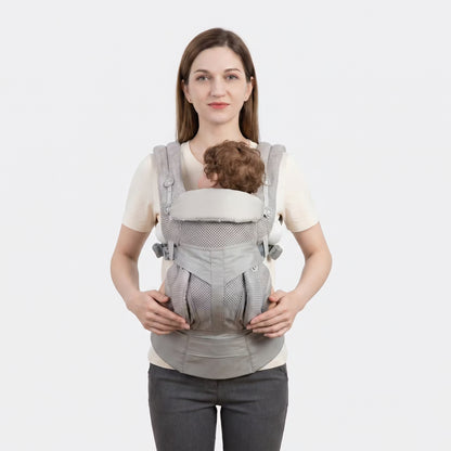 Woman wearing a baby in a gray baby carrier against a white background