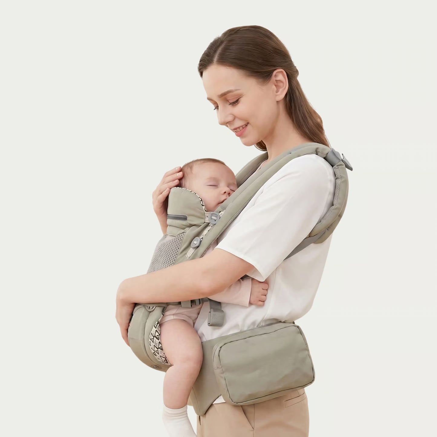 Woman holding a baby in a green baby carrier against a white background