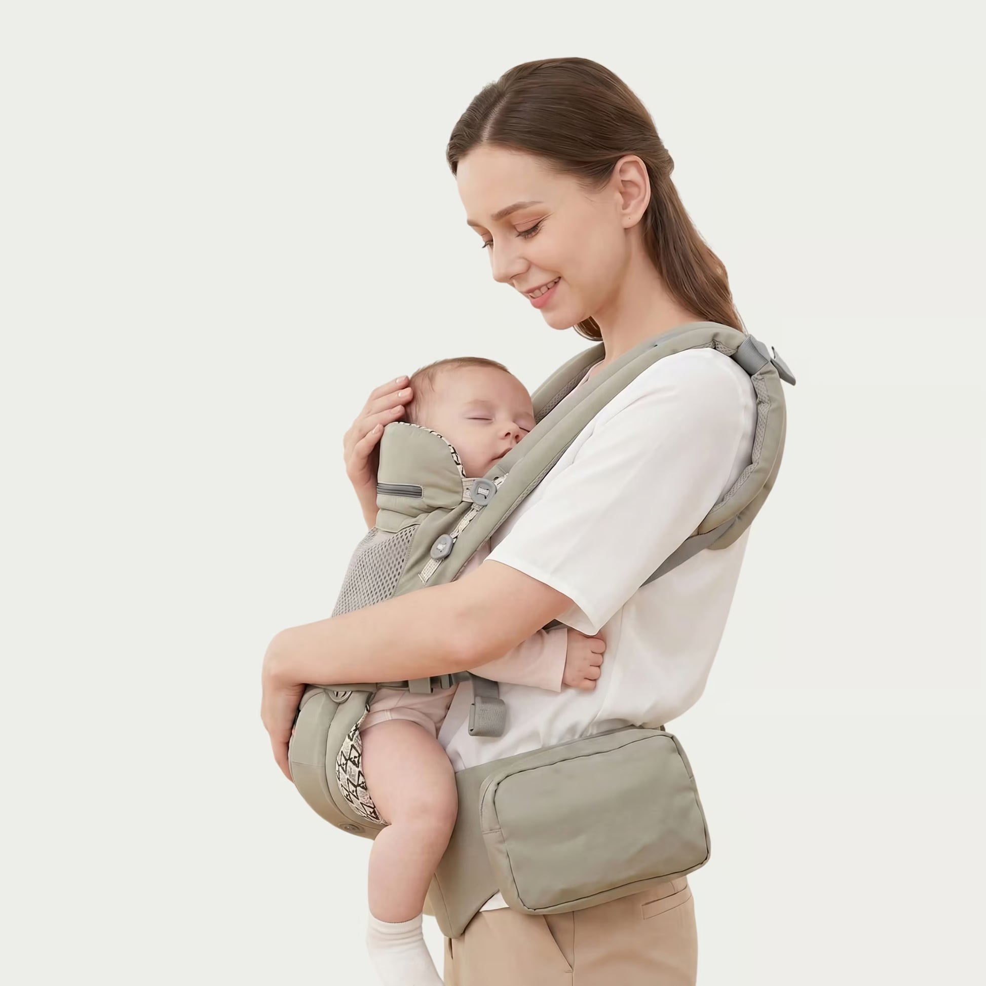 Woman holding a baby in a green baby carrier against a white background