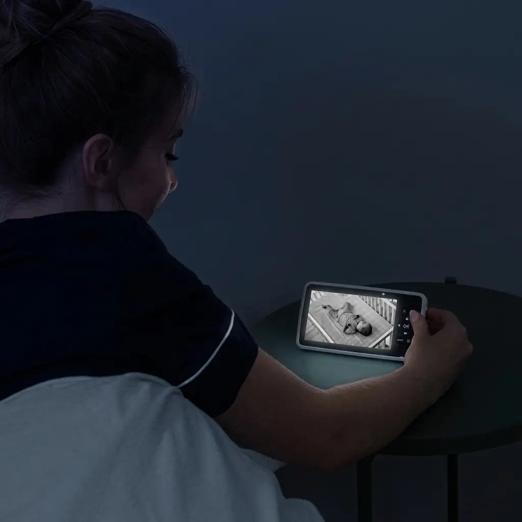 Person sitting in bed using a tablet in a dimly lit room