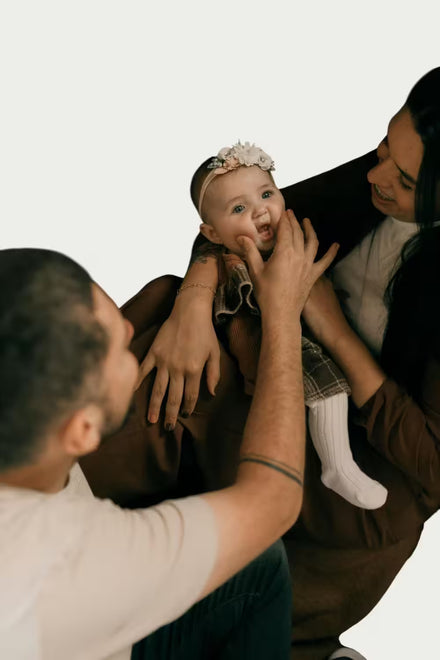 Two adults holding a baby against a white background
