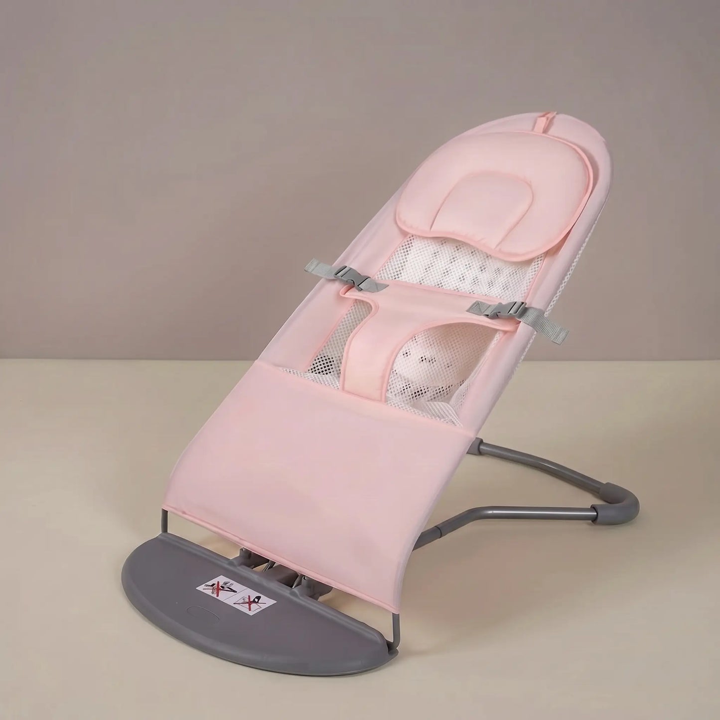 Pink baby bouncer on a beige surface with a neutral background